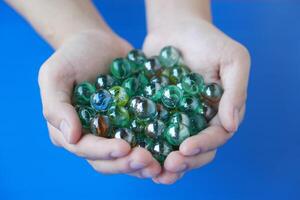 Close up hands holds marbles balls, small spherical object often made from glass, clay, steel, plastic, or agate. Concept. object use as toy for playing games or use for DIY craft decoration. photo