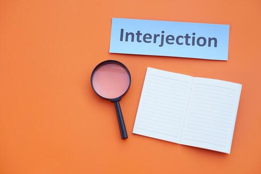 Paper word card with text Interjection, magnifying glass and blank page notebook. Concept English language teaching. Educational materials. Teaching aid. Grammar lesson photo