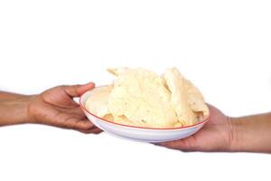 Close up hands holds plate of crisp rice cakes, traditional food. on white background. Concept, giving , serving and sharing food. Traditional Thai snack, made from dried dough and deep fry. photo