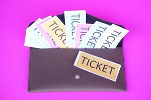 Leather envelope full of paper tickets. Pink background. Concept, tickets for passing or enter to join activity or public vehicles. Tickets for playing games. Teaching aids. photo