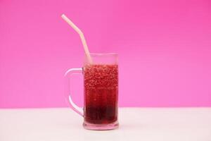 Glass of red fruit smoothie with drinking straw, pink background. Concept, healthy beverage for health. Well being and weight loss menu. Homemade refreshing drinks. High fibers, detox. photo