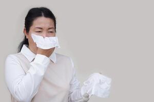 Asian woman hold white tissue paper to cover her mouth or clean runny nose with snot from cold or allergy symptoms. Concept, Health problems. Cover mouth when cough or sneeze to stop spreading of germ photo