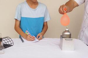 Unidentified boy is studying about science experiment about balloon burning on fire. The expanding of air pressure , reaction of chemical substance. Concept, education. photo