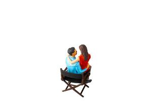 Miniature people , young man and woman sit together on chair Isolated on white background with clipping path photo