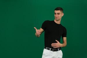 cool man holding symbol emotions of a handsome man guy on a green background chromakey close-up dark hair young man photo