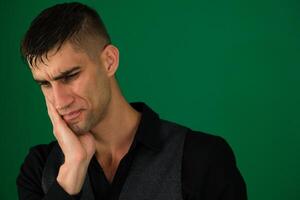 hombres dolor de muelas emociones de un hermoso hombre chico en un verde antecedentes chromakey de cerca oscuro pelo joven hombre foto