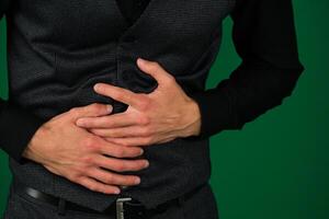 Man posing in a suit Abdominal pain emotions of a handsome man guy on a green background chromakey close-up dark hair young man photo