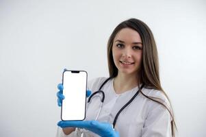 Portrait of medical doctor woman with stethoscope and phone in hands. Isolated on white background. photo