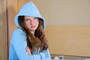 Side view young woman looking away at window sitting on couch at home. Frustrated confused female feels unhappy problem in personal life quarrel break up with boyfriend or unexpected pregnancy concept photo