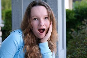 Close up portrait of a beautiful young woman with surprised expression looking at camera. Unbelieving, outdoor. photo