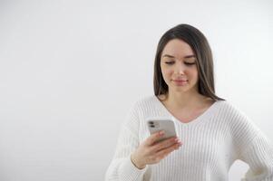 The image of a young hipster girl sitting in a cozy home interior and using a modern smartphone, women's hands typing a text message on a mobile phone, the concept of social networks photo