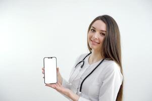 Female doctor in lab coat on white background isolated, confident smile hold white paper blank with empty space photo