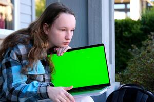 young pretty student woman bored tired over worked on her laptop wearing a black shirt isolated on green screen cromakey - chormakey or chroma croma key for composite photo