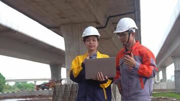 Asian male and female engineers Inspecting construction work radio command concrete road bridge highway video