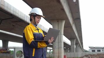 Asian female engineer uses laptop to inspect highway construction work video