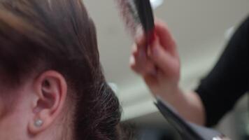 close-up of a hairdresser drying and styling a woman's hair with a comb. Stylish fashionable hairstyle made by a professional in an elephant outfit. High quality 4k footage video