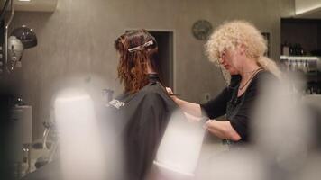 un mujer peluquero hace un Corte de pelo para un cliente. belleza procedimientos en el del estudio profesional salón. alto calidad 4k imágenes video