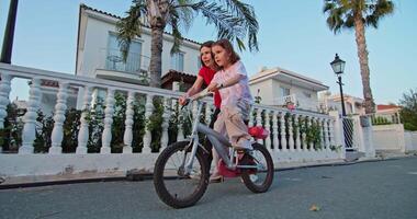 Cherished Moments. A Mother's Loving Guidance as Her Daughter Learns to Ride a Bicycle, Embracing the Joy of Parental Support and Happy Childhood Memories. High quality 4k footage video