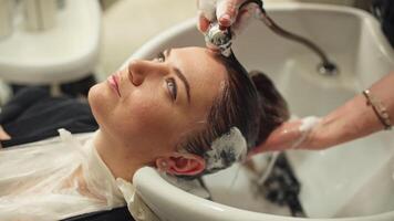 Female Hairdresser Washes Client's Hair Before Styling and Coloring, Preparing for Beauty Procedures in Beauty Salon, Highlighting Care Professionalism in Client Service and Women's Beauty Lifestyle video