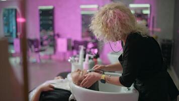 salão transformação. fêmea cabeleireiro lavagens do cliente cabelo, prepara para cortar e cor, beleza serviço e estilo de vida. Alto qualidade 4k cenas video