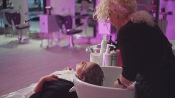 ein weiblich Friseur wäscht ein Mädchen Haar im ein Schönheit Salon. Haar Färberei Verfahren, Aussehen Pflege. hoch Qualität 4k Aufnahmen video