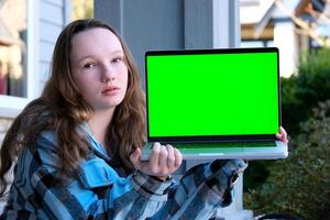 teen Girl show laptop with empty mockup green chroma key screen, It expert, technician repair service, tech support maintenance education school advertising entertainment internet games photo