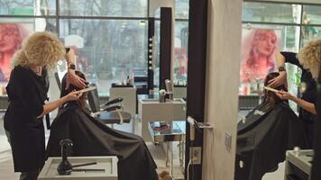 une femme dans une beauté salon obtient une la Coupe de cheveux tandis que séance sur une chaise. une coiffeur coupes une les filles cheveux avec ciseaux. haute qualité 4k métrage video