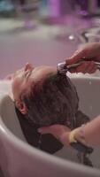 salon expérience. femelle coiffeur fournit cheveux laver pour client avant Couper et couleur, démontrant haute qualité un service et attention à détail dans beauté procédures et mode de vie. haute qualité 4k video