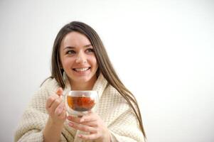 retrato de alegre joven mujer disfrutando un taza de café a hogar. sonriente bonito niña Bebiendo caliente té en invierno. emocionado mujer vistiendo gafas y suéter y riendo en un otoño día. foto