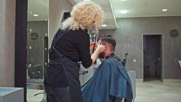 Crafting the Perfect Look. Woman Hairdresser Using Clippers to Sculpt a Man's Hair in a Salon, Emphasizing Care for Appearance and Image. High quality 4k footage video