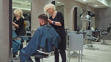 Elevating Style. Skilled Female Stylist Enhancing a Man's Hair with Clippers in a Beauty Salon, Highlighting Professional Care and Attention to Detail. High quality 4k footage video