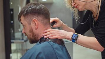 Friseur Barbier macht ein Haarschnitt mit Schere zu ein Mann im ein Salon. nehmen Pflege von das Schönheit und Gesundheit von das Haar, das Jungs Haarschnitt ist gemacht durch ein Fachmann. hoch Qualität 4k Aufnahmen video