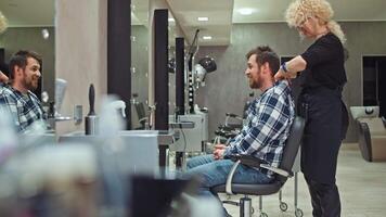 Artistry in Action. Female Hairdresser Using Clippers to Create a Polished Look for a Man's Hair in a Beauty Salon, Showcasing Professionalism and Personal Care. High quality 4k footage video