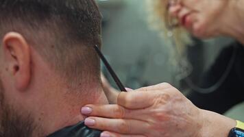 detailopname van een kapper snijdend een man's haar- met een klipper. haar- zorg, kapsel in een schoonheid salon, kapperszaak door een kapper. hoog kwaliteit 4k beeldmateriaal video