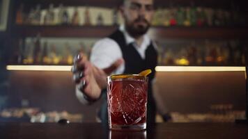 Bartender serves the visitor a red cocktail with an orange negroni, the hand takes a glass video