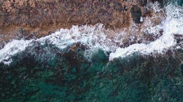 aéreo Visão do oceano ondas quebra em uma rochoso costa. abstrato natureza fundo . Alto qualidade 4k cenas video