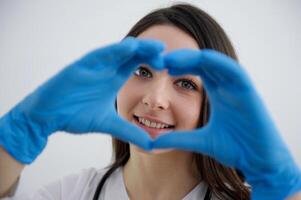 beautiful young girl nurse showing heart in blue gloves doctor surgery helping people care treatment hippocratic oath love photo