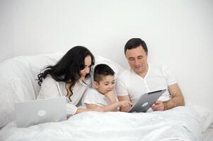 dad Mother and son under the blanket with a digital tablet. kid dream online night games at concept. family watching online under covers with digital tablet. social media photo