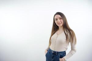 Portrait with copy space, empty place of trendy, cheerful, modern girl in denim outfit, holding hands in pocket of jeans, looking at camera, having short hair, isolated on grey background photo