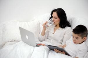 diet weight loss woman drinks water in bed while working on computer son plays tablet proper nutrition Healthy way of life coronavirus quarantine spend time Alone with yourself in circle of loved ones photo