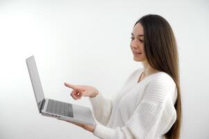 hermosa niña ordenador portátil en su manos puntos dedo a el pantalla largo pelo publicidad interesante contenido negocio, oficina, colegio y educación concepto sonriente mujer de negocios con pantalla táctil en oficina foto