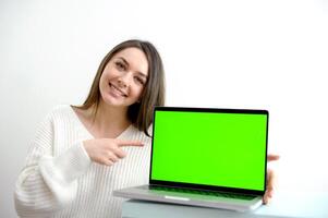 girl pointing her finger at screen monitor Rear view woman freelancer using laptop computer with a green screen on monitor. Concept remote work, freelance, working on laptop computer or net-book. photo