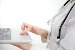 Close up woman doctor working on laptop, typing on keyboard, therapist physician nurse sitting at work table in hospital office, using medical apps, consulting online, writing report photo