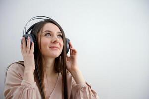 Happy girl with headphones listens to music on a white background Young girl wearing headphones and listening to music photo