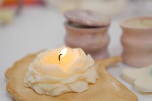 lit burning candle in the form of a rose with wax petals against background of massage candles spa salon interior beautifully burning fire relaxation pleasant time beauty self care massage treatments photo