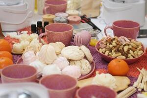 marshmallow tea cups delicious snack nuts dried fruits and tangerines on the table sweets good presentation healthy self-care treats for guests on a wicker woolen tablecloth napkin photo
