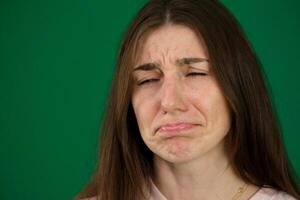 A portrait of a moody Caucasian girl isolated on orange background. She's dissapointed and sad, looking sideways and pouting lips photo