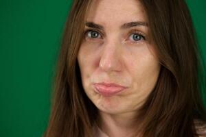 Image of resentful brunette woman posing and looking aside isolated emotions of a young girl on a green background chromakey beautiful facial features real people pink T-shirt white skinned. European photo