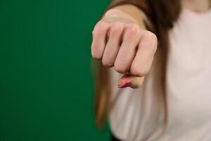 young female fist straight to camera, isolated body parts of a young woman on a green background chromakey photo