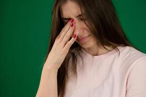 Portrait of unhappy young woman Woman with pained expression different emotions of a young girl on green background chromakey beautiful facial features real people pink T-shirt white skinned. European photo